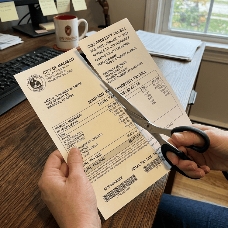 Hands cutting a City of Madison 2023 property tax bill with scissors